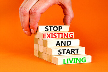 Stop existing start living symbol. Concept words Stop existing and start living on wooden blocks. Beautiful orange table orange background. Business Stop existing start living concept. Copy space.