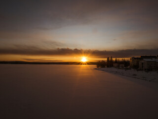 Sunset behind a snowy forest landscape and frozen river in Rovaniemi, Finland.