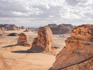 The view of car tracks and rocks in the sand of Valley of Agabat, White Desert, Egypt.