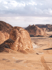 The view of car tracks and rocks in the sand of Valley of Agabat, White Desert, Egypt.