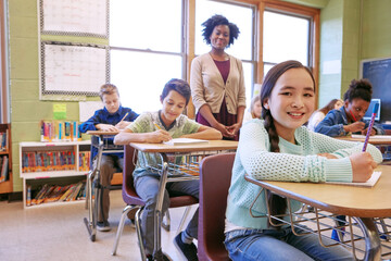 Learning, teacher and portrait of a girl with a smile to study, writing and test at school. Happy,...