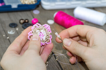 Making of handmade jewellery. Box with beads, spool of threads, needle on wooden background. Handmade accessories