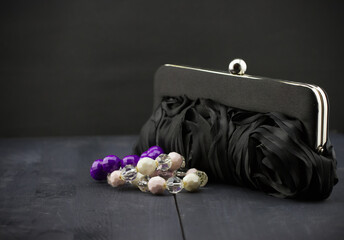 The black woman's handbag and bracelets of beads on dark wooden background