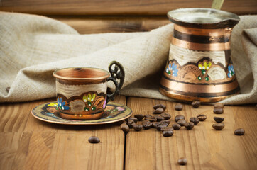 Traditional Turkish coffee set: vintage copper cup with coffee turk and roasted coffee beans on wooden table