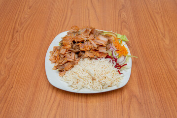 A great plate of rice kebab with salad and mixed meat of chicken and lamb on cherry wood table