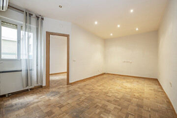 Room of an empty house with oak parquet flooring with slats arranged in the form of a chessboard, windows with curtains and oak woodwork
