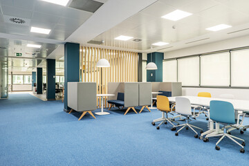 A coworking office with a boardroom table and meeting booths, wooden latticework and blue carpeted...