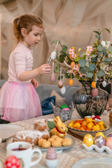 Happy baby child decorating the table for an Easter lunch. Happy easter! Smiling kid in enjoying Easter holiday