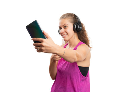 Woman in gym attire taking selfie using phone with headphones on