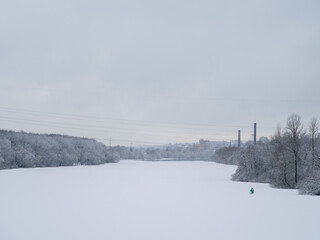 winter snowy landscape. frozen river, city in the distance