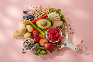 Colorful composition of healthy fruits veggies berries and nuts on round chopping board