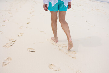 man in shorts walking on the beach
