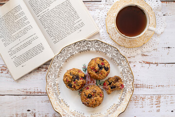 plate of berry muffins with coffee and book