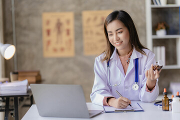 Asian female doctor working at desk with online consultation on medicines and treatments in doctor...