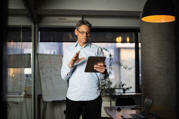 Portrait of businessman in office. Man using digital tablet. Businessman having video call.