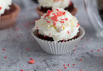 Coffee with muffins, muffins with cream and sprinkles. On a concrete background