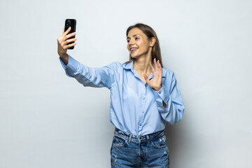 Portrait of a businesswoman taking selfie with mobile phone isolated over white background