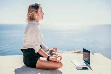 Woman sea laptop yoga. Business woman freelancer in yoga pose working over blue sea beach at laptop and meditates. Girl relieves stress from work. Freelance, digital nomad, travel and holidays concept