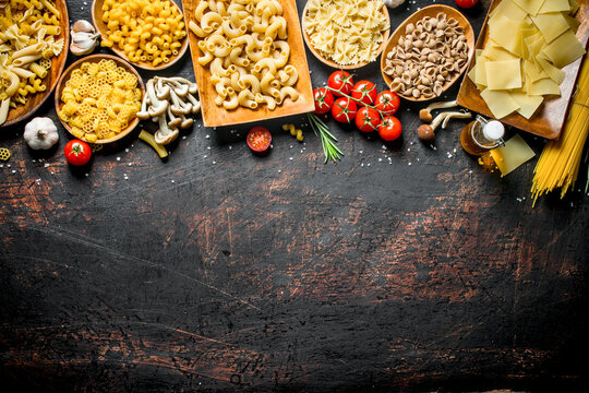Assortment of different types of raw pasta with mushrooms, tomatoes and garlic.