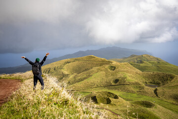 Happy woman with raised arms enjoying the views of the central highlands on São Jorge island,...