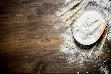 Obraz na płótnie Canvas Flour in a bowl with grains and spikelets.