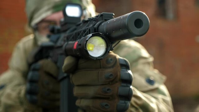 Close-up of a soldier in uniform and uniforms aiming a sniper rifle, the muzzle of a rifle close-up. Military conflict. Airsoft.