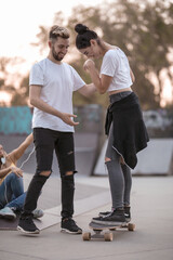 Young man helping a girl stand on a skateboard