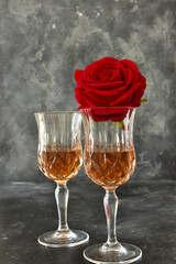 Close up two glasses of liquor and a rose on a black background.