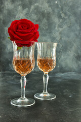 Close up two glasses of liquor and a rose on a black background.