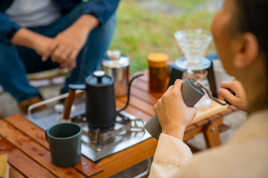 Group of Asian Man and woman friends having breakfast and making brewed coffee at camp in the morning. People enjoy and fun outdoor lifestyle travel nature and camping together on summer vacation.