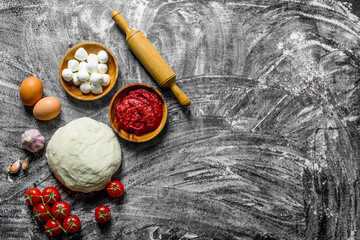 Preparation pizza. Dough with sauce, mozzarella and tomatoes.