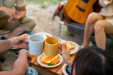 Group of Asian people enjoy and fun outdoor lifestyle travel nature and camping together on summer travel vacation. Man and woman friends having breakfast and drinking coffee at camp in the morning