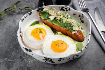 Two fried eggs for breakfast with avocado toast and salad on a plate. Healthy breakfast on the table