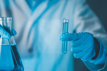 Scientist hand hold test tubes and erlenmeyer flask filled with blue sample chemicals in chemistry...
