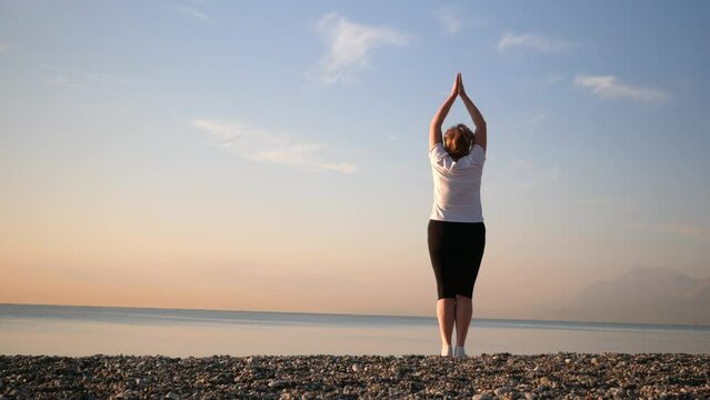 woman doing yoga performing asanas and enjoying life on the beach sea, sunset time