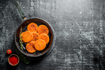 Fish cutlets in a old pan with the thyme and tomato sauce in a bowl.