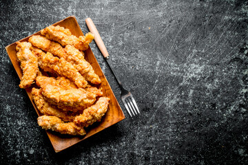 Chicken strips on a plate with a fork.