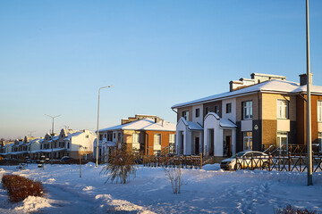 Fototapeta na wymiar Modern village house in winter day and trees near it in snow in sunny day