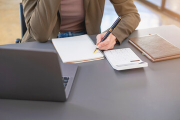 Marketing, Finance, Accounting, Planning, Businesswoman of bi nationality is talking with a customer representing a company distributor using a smartphone with laptop pen and notepad on office desk.