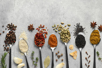 Metal spoons with different spices on light grey table, flat lay. Space for text