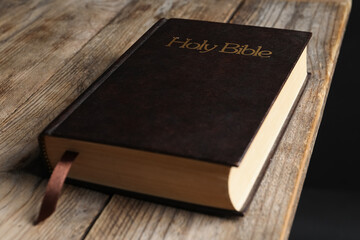 Bible with dark cover on wooden table. Christian religious book