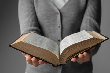 Woman reading Bible against grey background, closeup