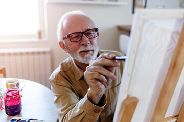 Senior creative art and craft professional painting an artwork in his home during a peaceful morning.