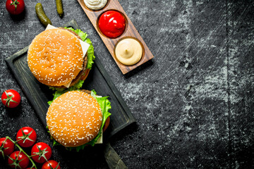 Burgers on the cutting Board and different sauces.