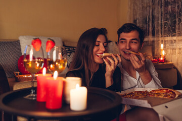 Valentines Day couple in love eating pizza drinking wine with strawberries having romantic dinner...