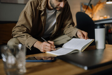 Young bearded man taking notes in home office, portrait.