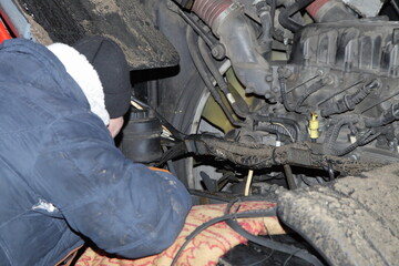 Repairman repairs a snapped alternator belt on heavy diesel truck at winter