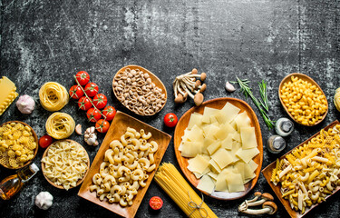 Different kinds of raw pasta with tomatoes and mushrooms.