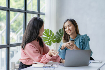 Two Asian female business colleagues meeting for a professional investor meeting at work and discussing a new marketing business strategy project.
