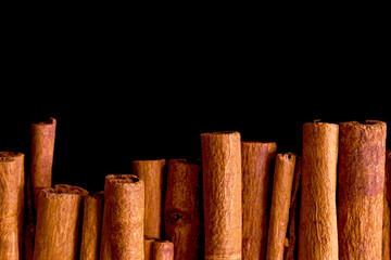 Cinnamon sticks isolated on black background. Lie in a row.